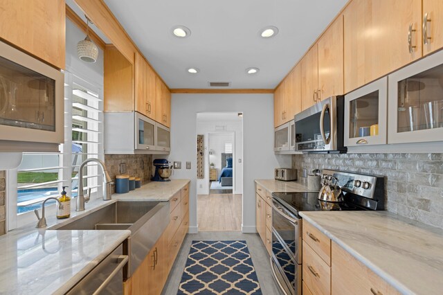 kitchen featuring a breakfast bar, light stone counters, decorative light fixtures, kitchen peninsula, and light brown cabinets