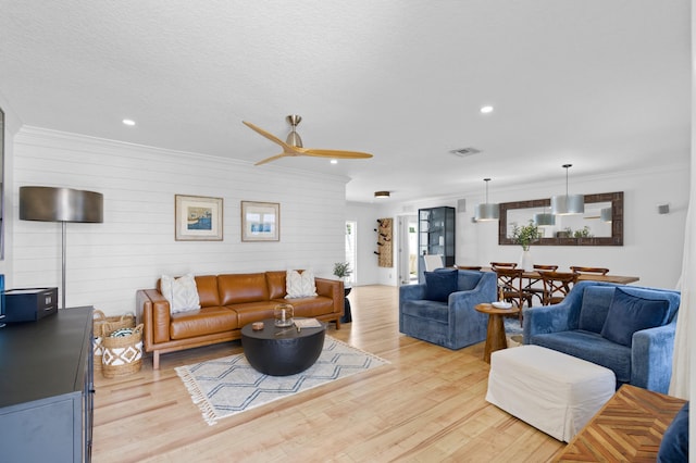 living room featuring crown molding, a textured ceiling, ceiling fan, and light hardwood / wood-style flooring