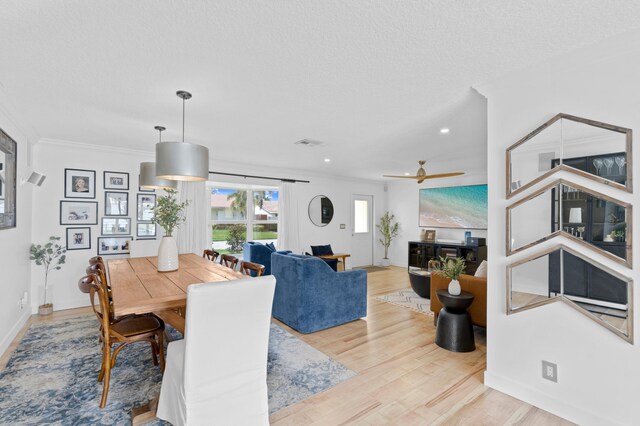 dining space featuring ornamental molding, a textured ceiling, and light wood-type flooring