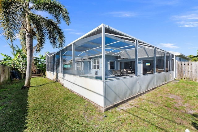 rear view of property with a pool, glass enclosure, and a lawn