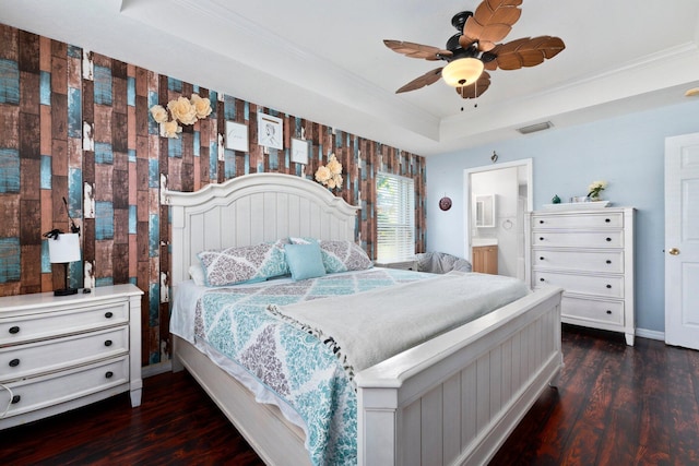 bedroom with connected bathroom, ceiling fan, a tray ceiling, and dark hardwood / wood-style floors