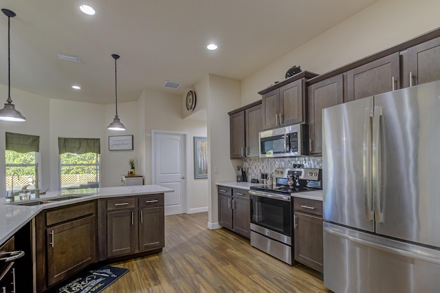 kitchen with decorative backsplash, dark hardwood / wood-style flooring, stainless steel appliances, sink, and decorative light fixtures