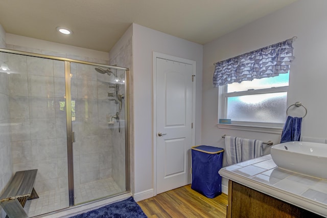 bathroom featuring hardwood / wood-style floors, a shower with shower door, and sink