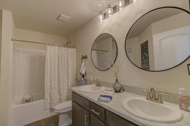 full bathroom with shower / tub combo, vanity, a textured ceiling, hardwood / wood-style floors, and toilet