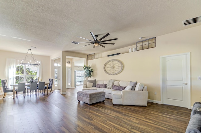 living room featuring a textured ceiling, dark hardwood / wood-style flooring, and ceiling fan with notable chandelier