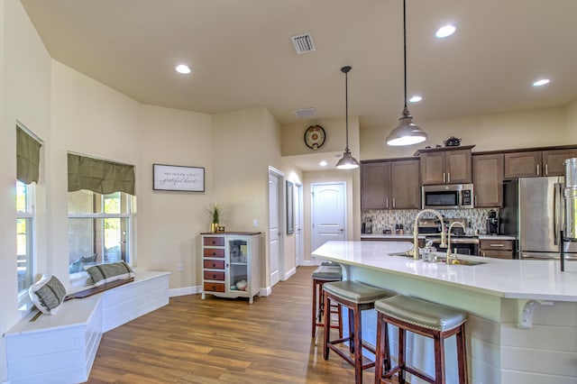 kitchen featuring sink, decorative light fixtures, a breakfast bar area, decorative backsplash, and appliances with stainless steel finishes