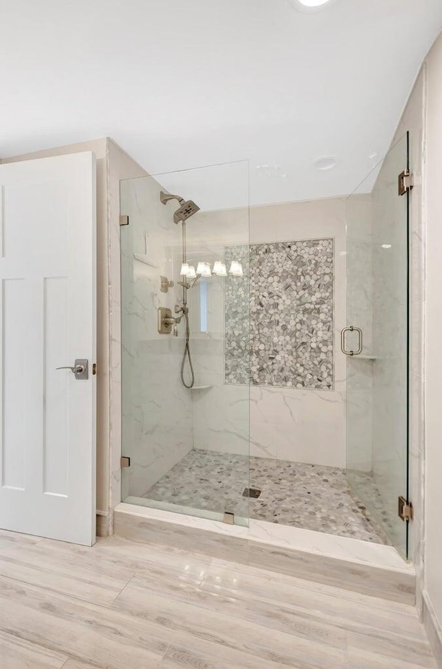 bathroom with a shower with shower door and hardwood / wood-style flooring