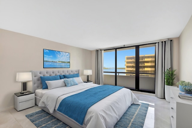 bedroom with a water view, light tile patterned floors, and access to outside