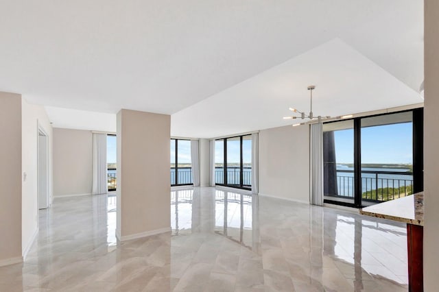 empty room with a chandelier, a wall of windows, a water view, and plenty of natural light