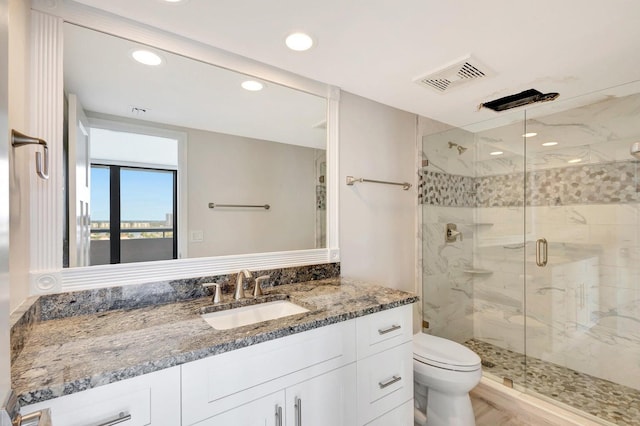 bathroom featuring a shower with shower door, toilet, and vanity