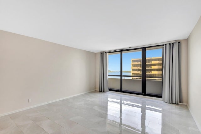 spare room with floor to ceiling windows and a water view