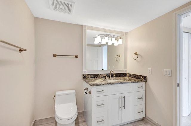 bathroom featuring toilet, vanity, and hardwood / wood-style floors