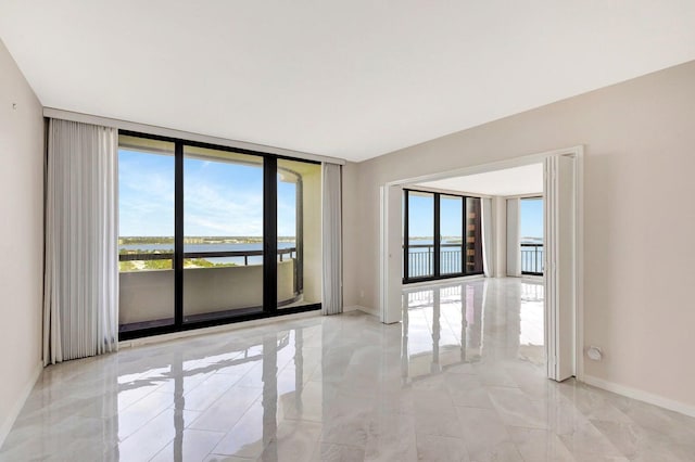 unfurnished room with a water view and expansive windows