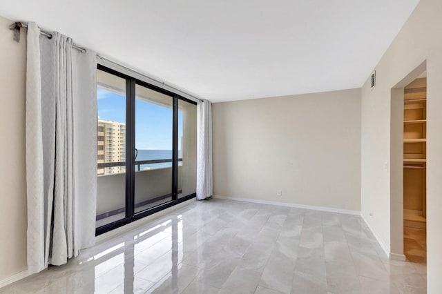 spare room featuring a water view and floor to ceiling windows