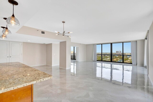 unfurnished living room featuring a notable chandelier and floor to ceiling windows