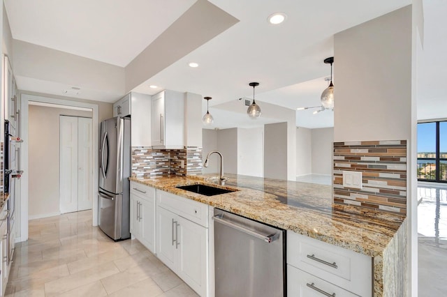 kitchen featuring pendant lighting, sink, white cabinetry, light stone countertops, and appliances with stainless steel finishes