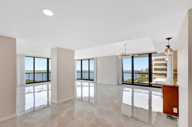 spare room with floor to ceiling windows, a water view, and an inviting chandelier