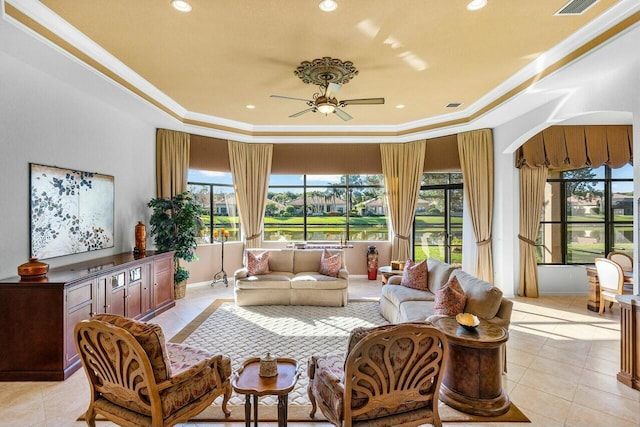 living room with ornamental molding, a raised ceiling, ceiling fan, and light tile patterned floors