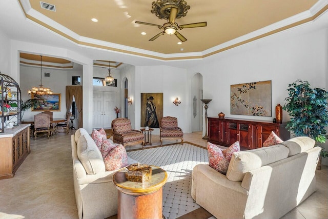 living room with ceiling fan with notable chandelier, a tray ceiling, and crown molding