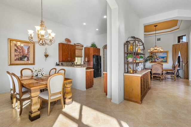 tiled dining space featuring a towering ceiling and an inviting chandelier