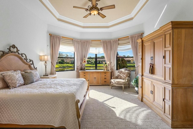 carpeted bedroom featuring ceiling fan, crown molding, and a raised ceiling