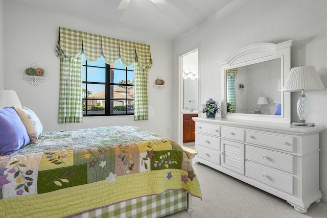 bedroom with ensuite bathroom, light carpet, and ceiling fan