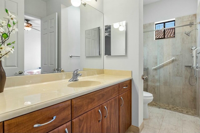 bathroom with toilet, tile patterned flooring, a tile shower, ceiling fan, and vanity