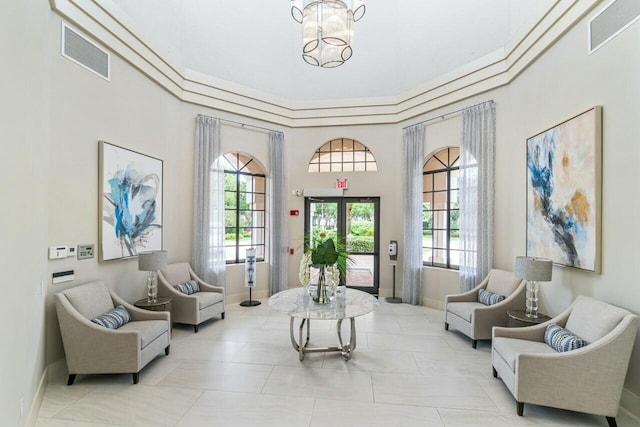 sitting room with a high ceiling, a notable chandelier, and a healthy amount of sunlight