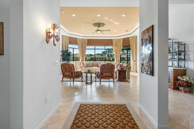 corridor with a raised ceiling, light tile patterned flooring, and crown molding