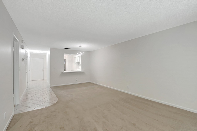 spare room featuring light colored carpet and a textured ceiling