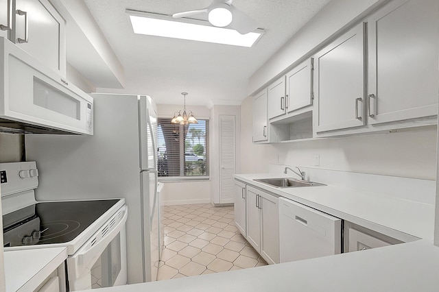 kitchen with white appliances, hanging light fixtures, ceiling fan with notable chandelier, white cabinets, and sink