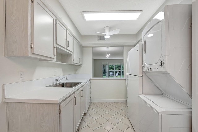 kitchen with stacked washer and dryer, white cabinetry, ceiling fan, and sink