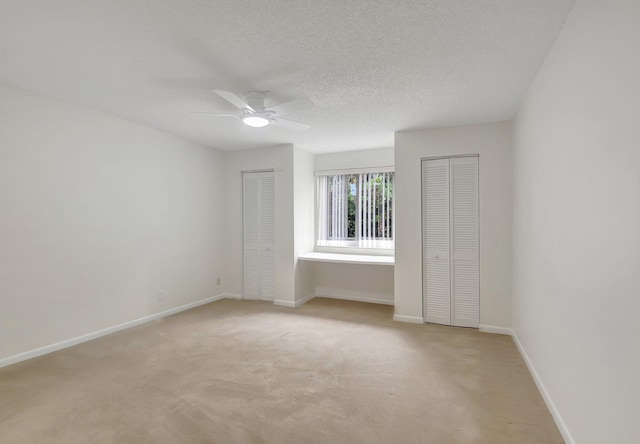 carpeted spare room with a textured ceiling and ceiling fan