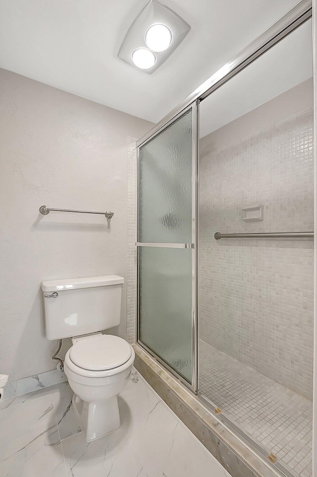 bathroom featuring a shower with shower door and toilet