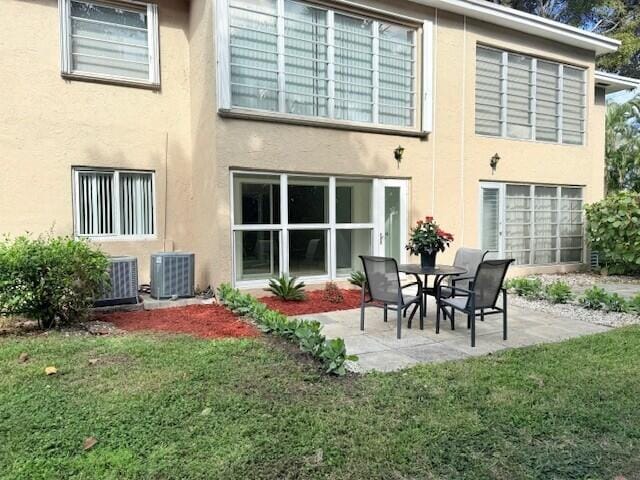 rear view of house featuring a patio, central AC, and a yard