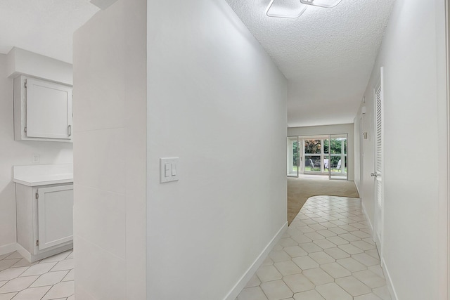 corridor with a textured ceiling and light tile patterned floors