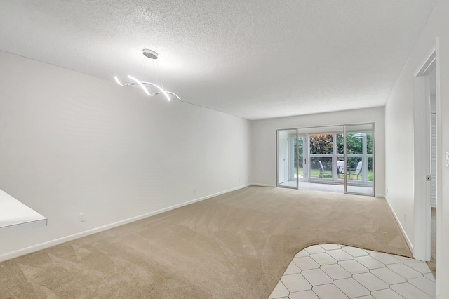 unfurnished room featuring a chandelier, light carpet, and a textured ceiling