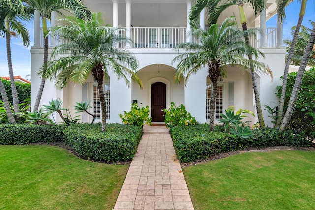 view of front facade with a balcony and a front lawn