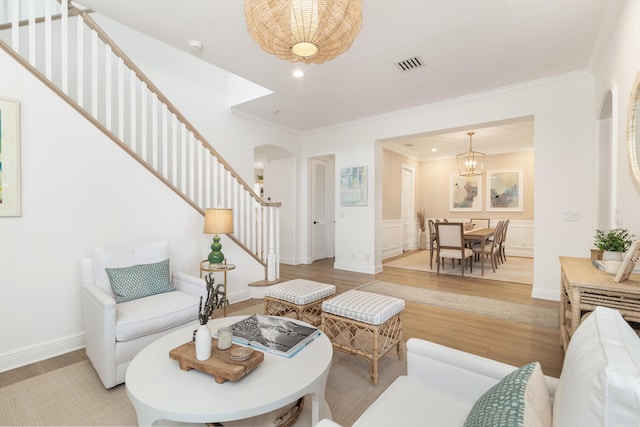 living room featuring crown molding, a chandelier, and light wood-type flooring