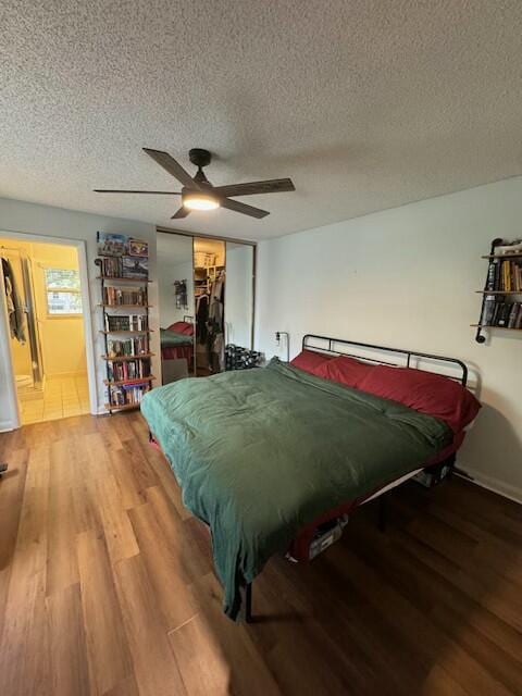 bedroom with ceiling fan, hardwood / wood-style floors, a textured ceiling, and a closet