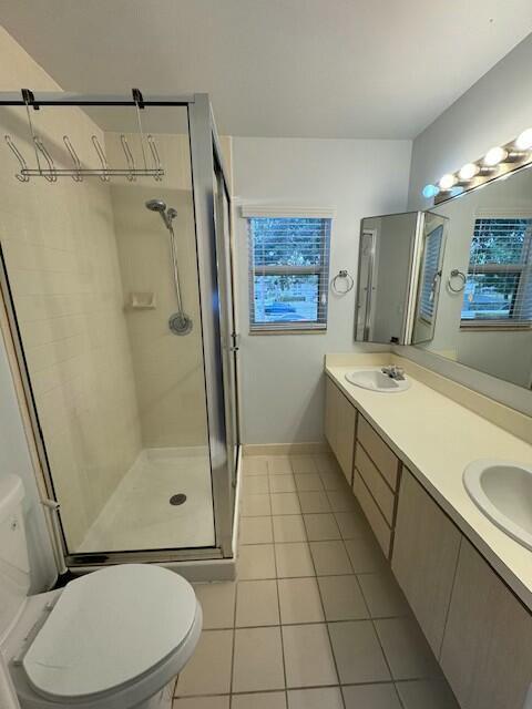 bathroom featuring tile patterned flooring, toilet, vanity, and a shower with shower door