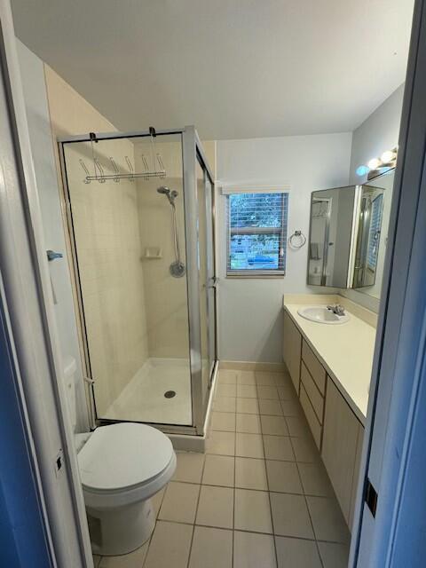 bathroom with tile patterned flooring, vanity, toilet, and a shower with door