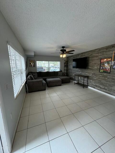 unfurnished living room with light tile patterned floors, ceiling fan, and wood walls