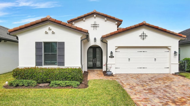 mediterranean / spanish-style home featuring a front lawn and a garage