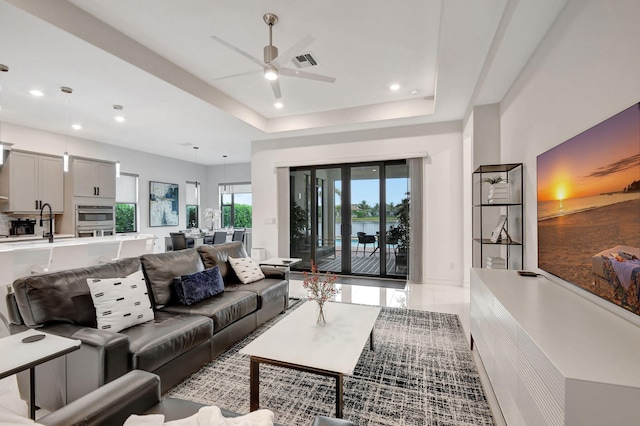 living room with sink, a raised ceiling, and ceiling fan