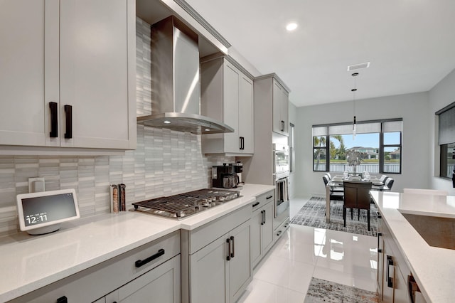 kitchen featuring stainless steel appliances, decorative light fixtures, light tile patterned floors, tasteful backsplash, and wall chimney range hood