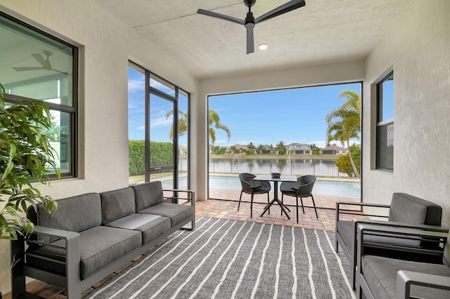 sunroom / solarium with ceiling fan and a water view