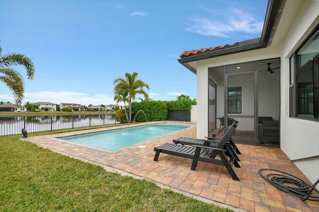 view of swimming pool with a lawn, pool water feature, a patio, and a water view