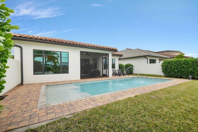 view of pool with ceiling fan, pool water feature, a sunroom, a yard, and a patio area