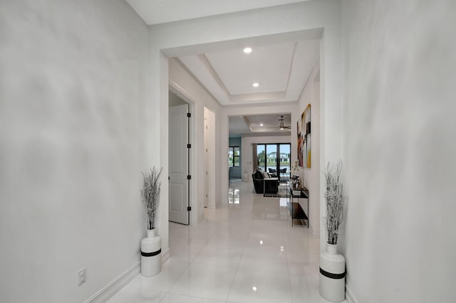 hall featuring a raised ceiling and light tile patterned floors